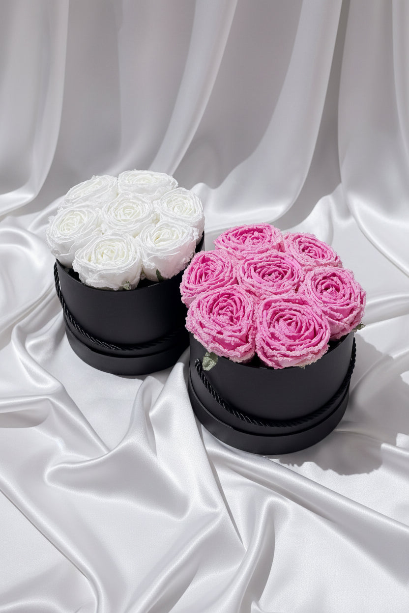 Two black cylindrical containers with white and pink rose bouquets on a dark background