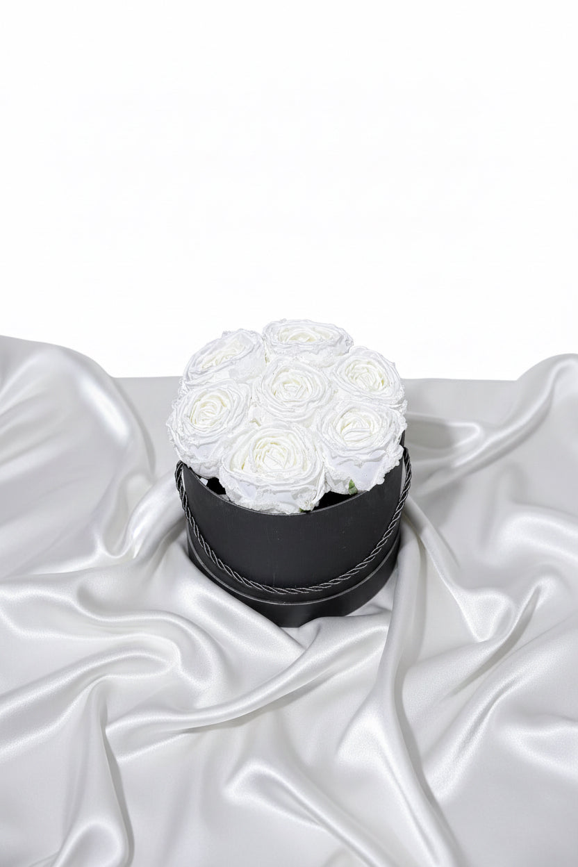 Black box with white roses on a silver satin surface