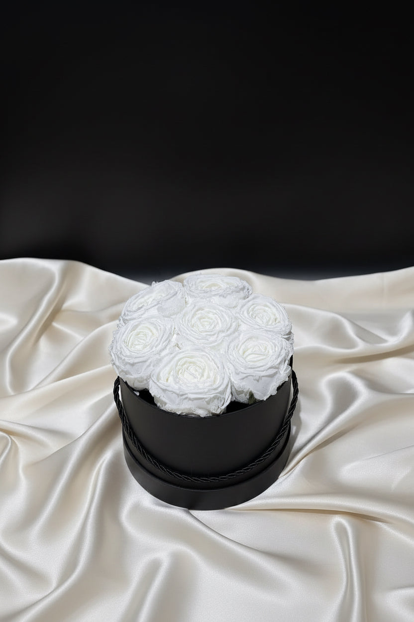 White flowers in a black box on a white fabric background